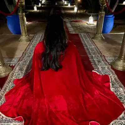 a woman in a red dress sitting on the floor at Amskou Camp in Merzouga