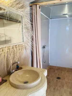 a bathroom with a sink with a glass shower at Amskou Camp in Merzouga