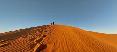 two people standing on top of a sand dune at Dar Tafouyte in Merzouga