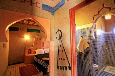 a bedroom with a bed and a bathroom with a shower at Dar Tafouyte in Merzouga