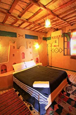 a bedroom with a bed with graffiti on the wall at Dar Tafouyte in Merzouga