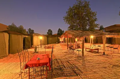 a group of tents with tables and chairs at night at Dar Tafouyte in Merzouga