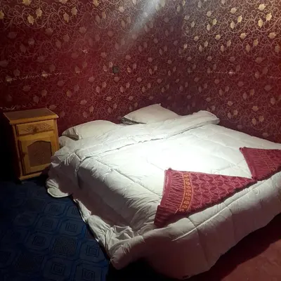 a bed in a bedroom with a red wall at RestCamp ErgChebbi in Merzouga