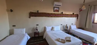 two beds in a room with white sheets at Chez Brahim vue panoramique in Aït Ben Haddou