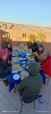 a group of people sitting around a table eating food at Afgo Hostel in Ouarzazate