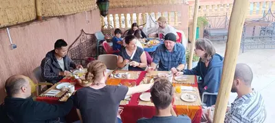 a group of people sitting around a table eating food at Hostel Afgo Rooftop in Ouarzazate
