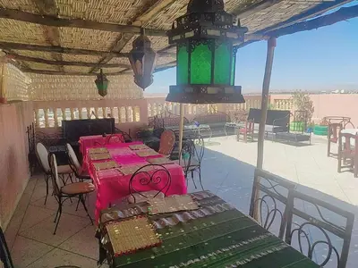a patio with tables and chairs and a green light at Hostel Afgo Rooftop in Ouarzazate