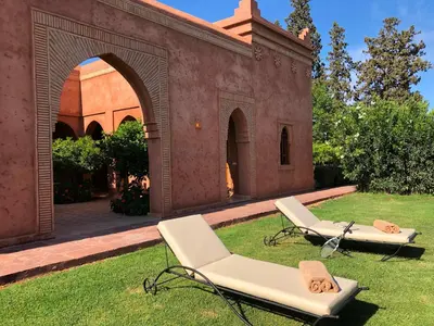 two lounge chairs on the grass in front of a building at Domaine Casa Cecilia in Marrakech