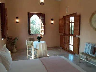 a bedroom with a bed and a table and a window at Domaine Casa Cecilia in Marrakech