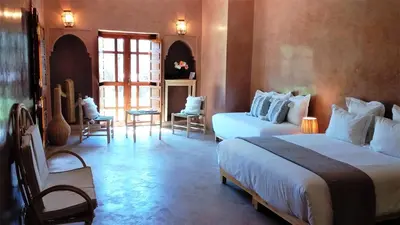 a bedroom with two beds and chairs in a room at Domaine Casa Cecilia in Marrakech