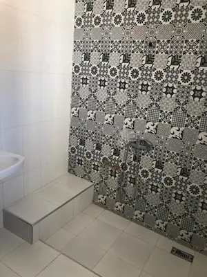 a bathroom with a shower with a tile wall at Riad Malak in Meknès