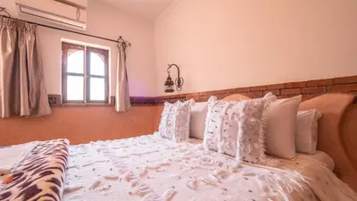 a bedroom with a bed with white pillows and a window at Riad Rihana Dades in Boumalne