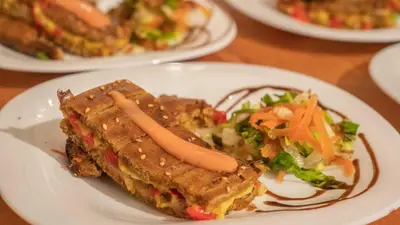 a white plate with a sandwich and salad on a table at Riad Rihana Dades in Boumalne