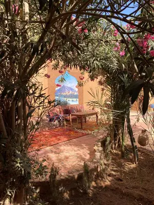 a bench in a garden with a painting on the wall at Dar M'hamid in Mhamid