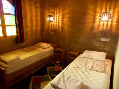 a room with two beds and a window at Chambres dans casbah - Gite D'étape Gorges De Ziz in Er Rachidia