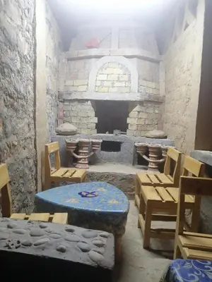a room with a stone fireplace with a table and chairs at Chambres dans casbah - Gite D'étape Gorges De Ziz in Er Rachidia