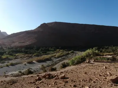 a view of a mountain with a river in the foreground at Chambres dans casbah - Gite D'étape Gorges De Ziz in Er Rachidia