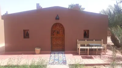 a small house with a door and a table and bench at Mhamid Auberge Saharaespace in Mhamid