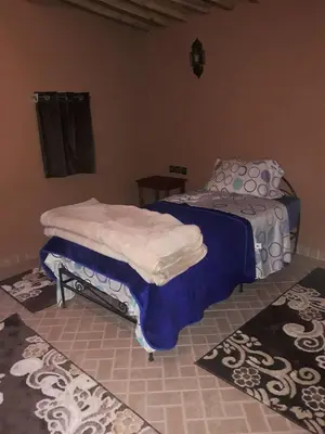 a bedroom with a bed and two rugs at Mhamid Auberge Saharaespace in Mhamid