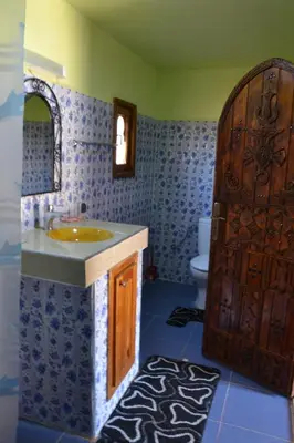 a bathroom with a sink and a wooden door at Mhamid Auberge Saharaespace in Mhamid
