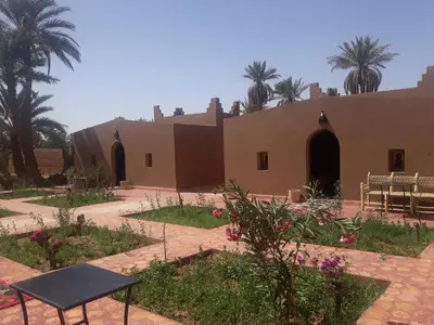 a building with palm trees in the background at Mhamid Auberge Saharaespace in Mhamid