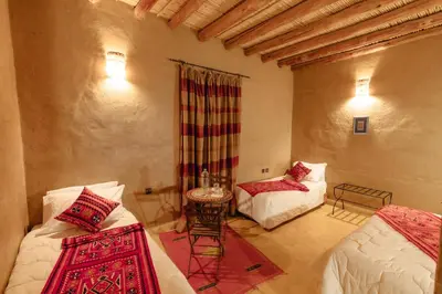 a room with two beds and a table in it at Dar El Janoub in Merzouga