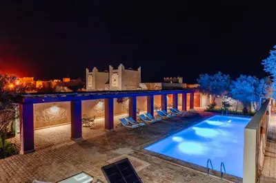 a villa with a swimming pool at night at Dar El Janoub in Merzouga