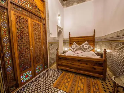 a bedroom with a bed in a room with patterns on the walls at Charming Riad Ouliya in Fs in Fès