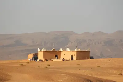 a building in the desert with mountains in the background at les dunes D'or in Tagounite