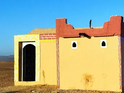 a building with a door in the middle of the desert at les dunes D'or in Tagounite