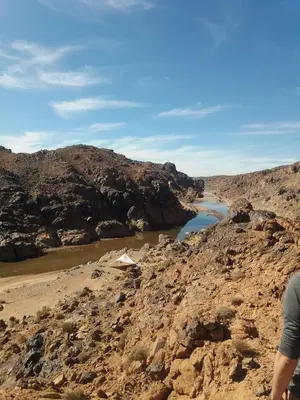 a person standing on the side of a river in the desert at kasbah Dar Bahnini in Skoura