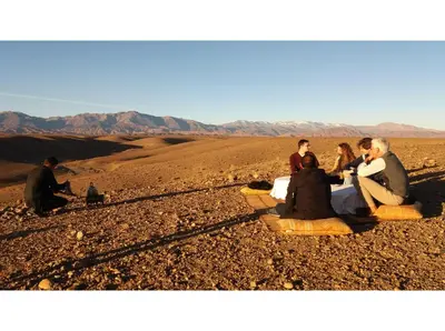 a group of people sitting on the ground in the desert at kasbah Dar Bahnini in Skoura