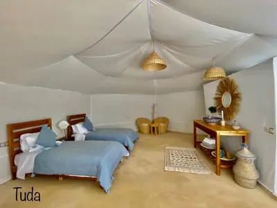 a bedroom with two beds and a tent at Tuda Luxury Camp in Merzouga