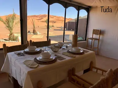 a table in a room with a view of the desert at Tuda Luxury Camp in Merzouga