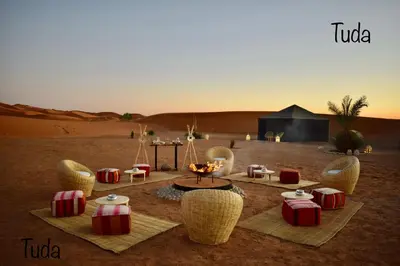 a room with chairs and a table in the desert at Tuda Luxury Camp in Merzouga