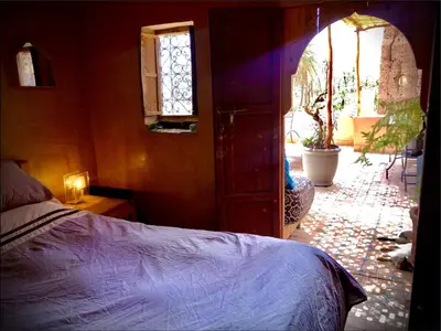 a bedroom with a bed and an open door at Maison d'hôte ''J'' in Agdz