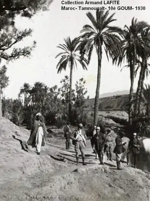 a group of men walking down a dirt road with palm trees at Maison d'hôte ''J'' in Agdz