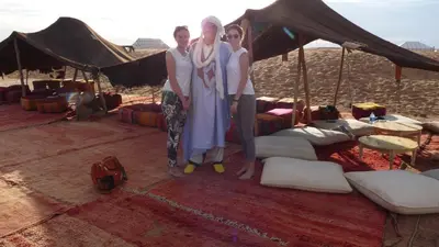 three women standing in front of a tent in the desert at Prends Ton Temps in Zagora