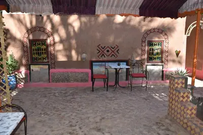 a patio with two chairs and a table and two windows at Prends Ton Temps in Zagora