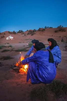 three people sitting around a fire in the desert at Exclusive 