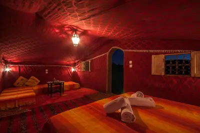 a room with two beds in a red room at Rêve du Sahara - Dar Azawad Desert Camp in Mhamid