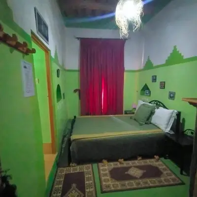 a bedroom with a bed with a red curtain at Kasbah ben Ali in Kalaat MGouna