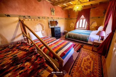 a bedroom with a bed and a window and a rug at Kasbah ben Ali in Kalaat MGouna