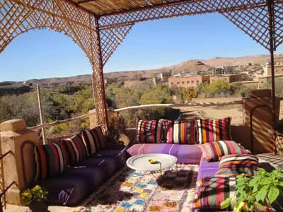 a patio with a couch and a table and mountains at Kasbah ben Ali in Kalaat MGouna