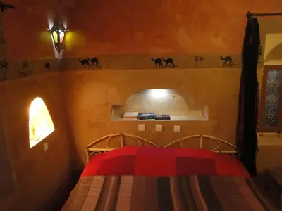 a bedroom with a bed and a shelf with cats on it at Kasbah ben Ali in Kalaat MGouna