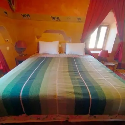 a bedroom with a bed with a colorful bedspread at Kasbah ben Ali in Kalaat MGouna