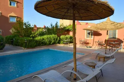 a patio with chairs and an umbrella and a pool at Kasbah Tussna in Boumalne