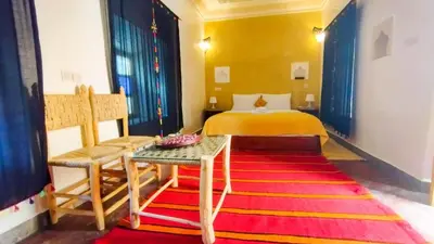 a bedroom with a bed and a red rug at Kasbah Tussna in Boumalne
