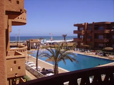 a view of a resort with a swimming pool and the ocean at Appartement high standing piscine jardin mer proche Mohammedia in Figuiq