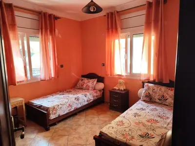 two beds in a room with orange walls and windows at Appartement high standing piscine jardin mer proche Mohammedia in Figuiq